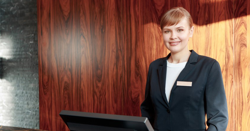 A hotel receptionist standing at a reception desk